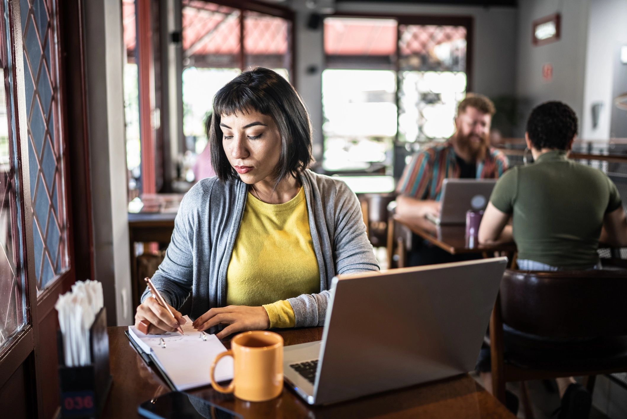 Writer taking notes while working on a laptop