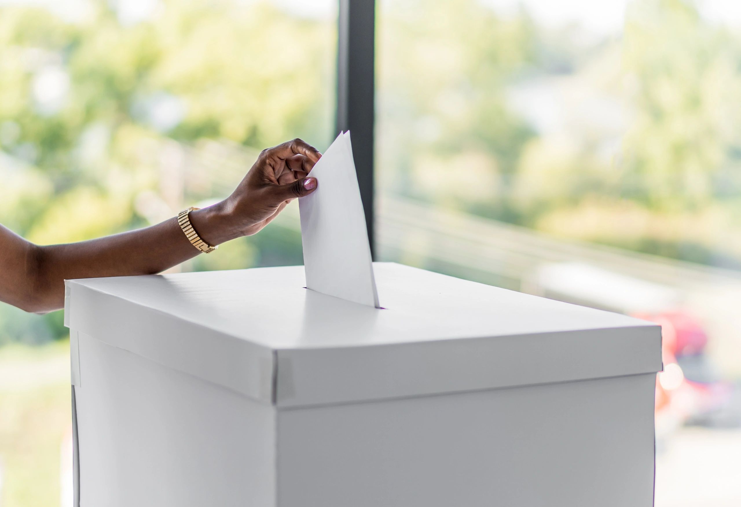 Hand casting ballot into a vote box