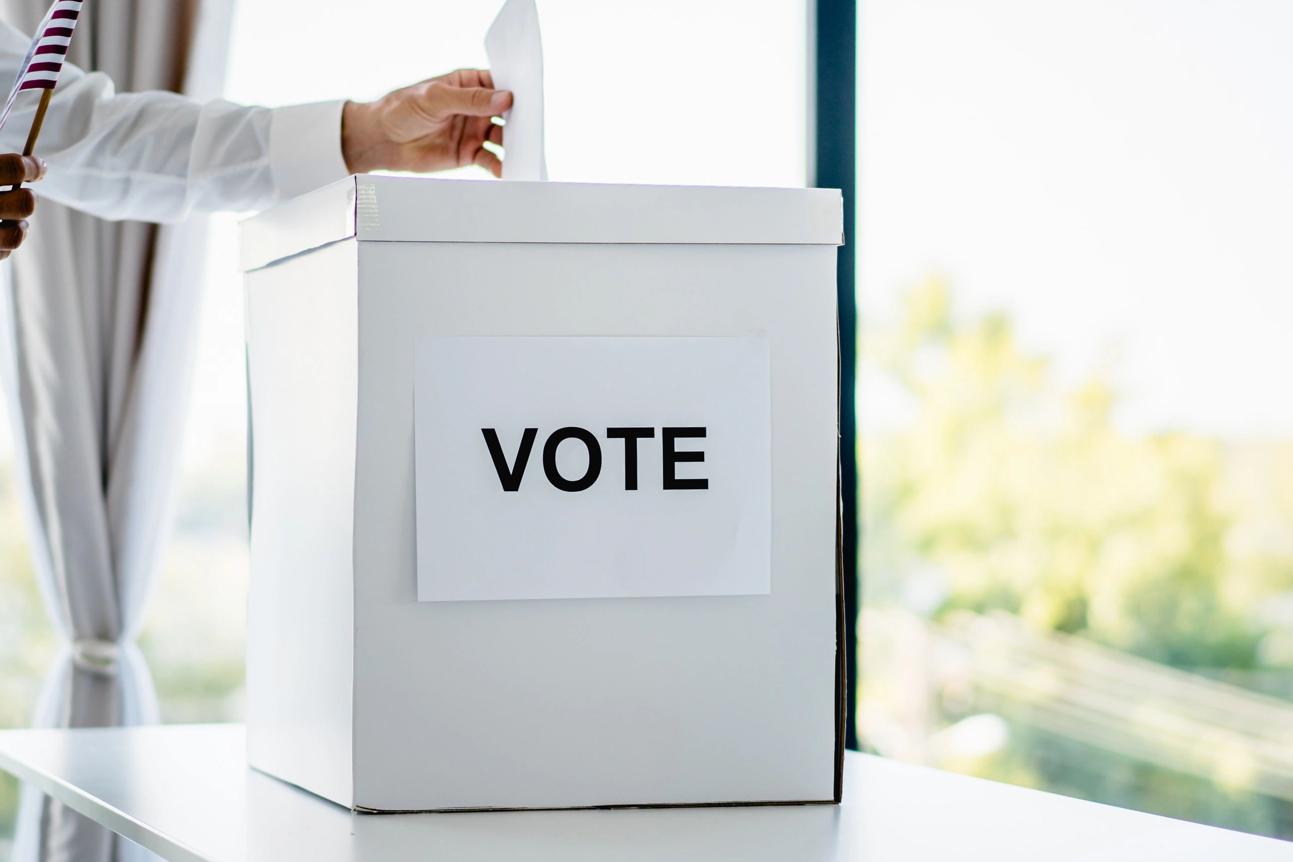 Hand casting a vote into a ballot box